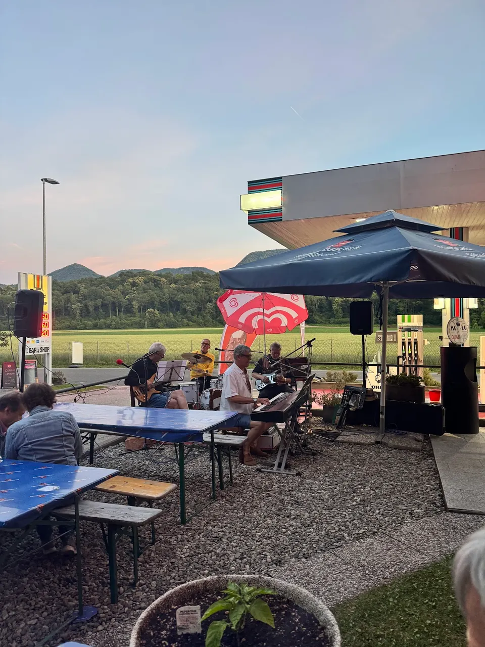 Un gruppo suona sotto l’ombrellone, al tramonto, davanti ai tavoli all’aperto