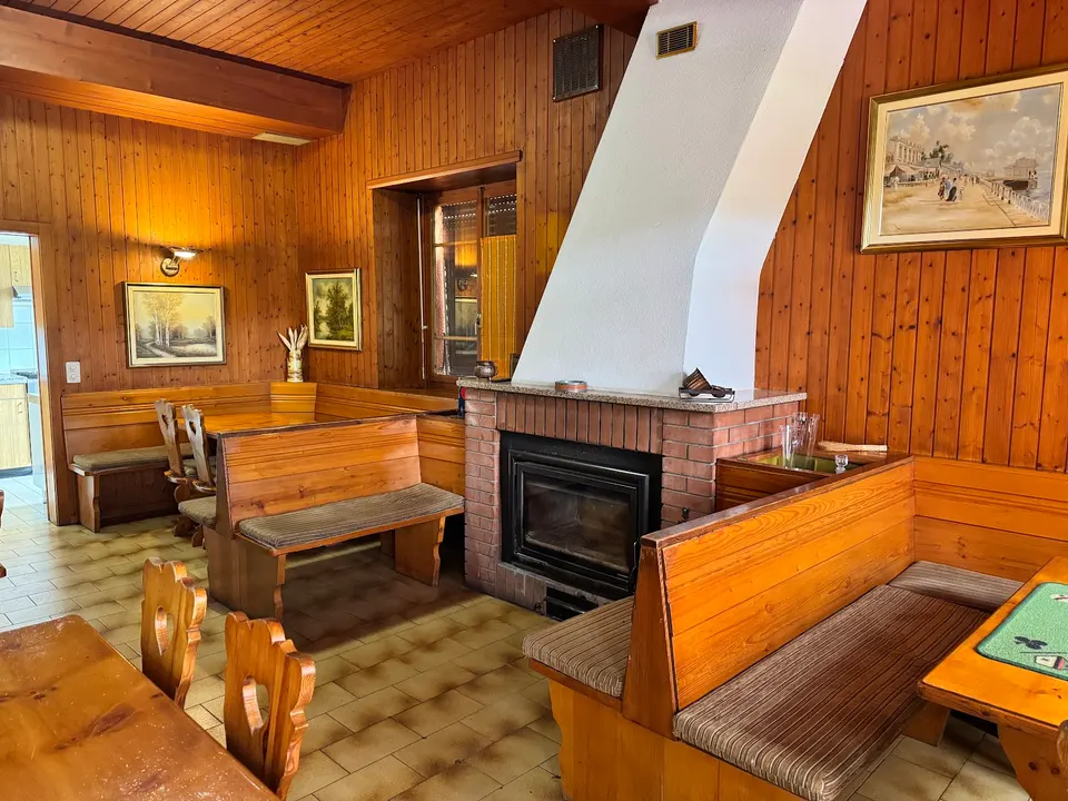 Sala interna rivestita in legno, con panche e camino