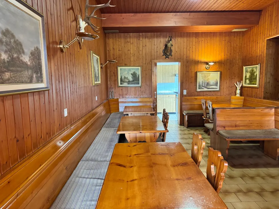 Sala in legno con tavoli lunghi, quadri alle pareti e un trofeo di cervo